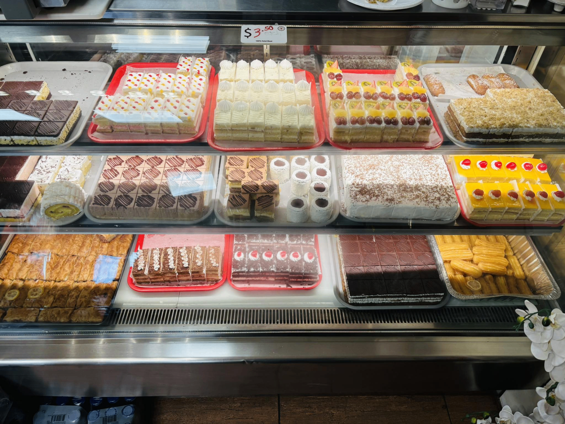 Bakery display case at USA Halal Meat Inc. filled with fresh cakes, baklava, and pastries