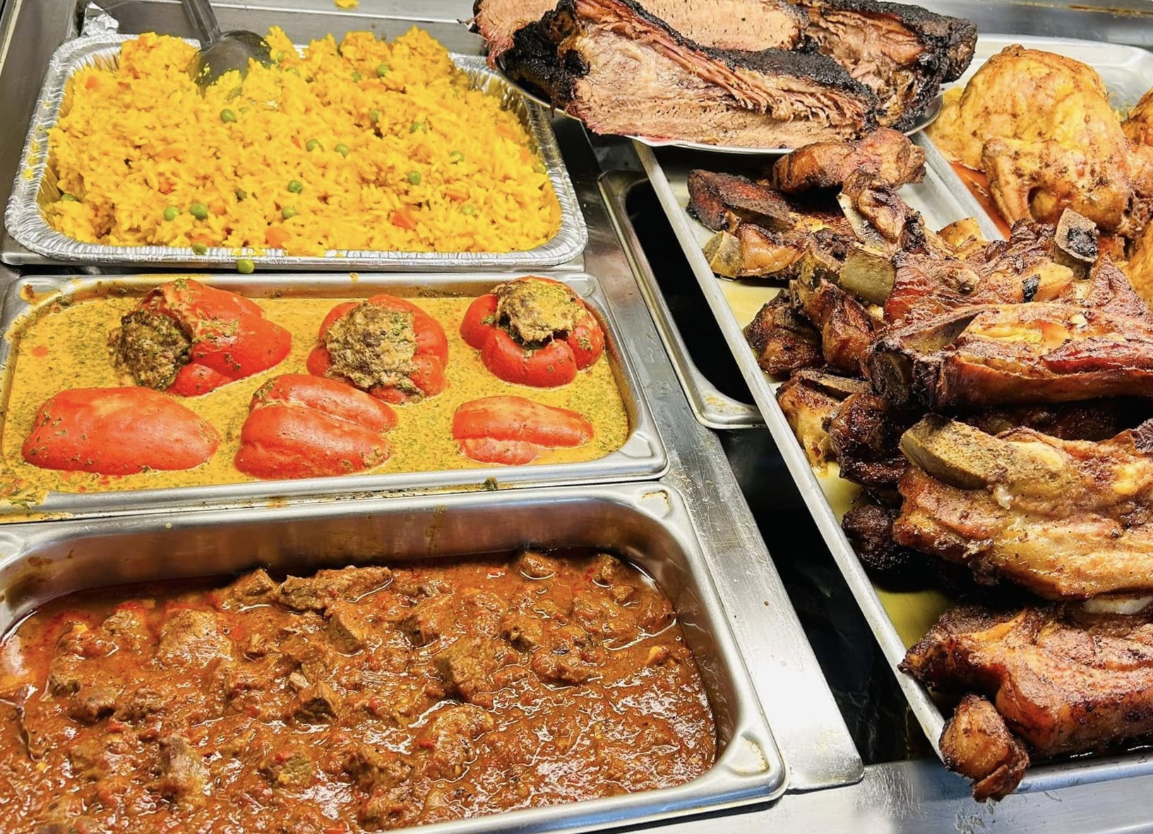 Trays of traditional Bosnian dishes — stuffed peppers, lamb stew, saffron rice and roasted meats on the hot food counter