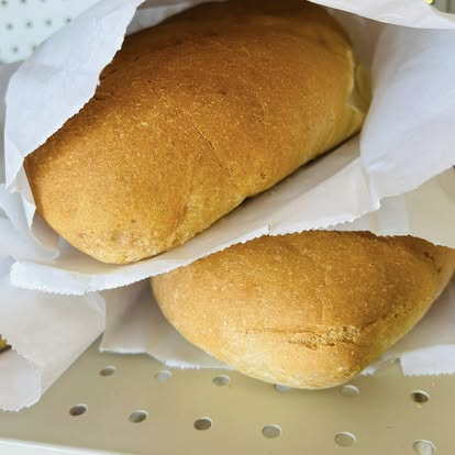 Two fresh-baked somun loaves nestled in white paper