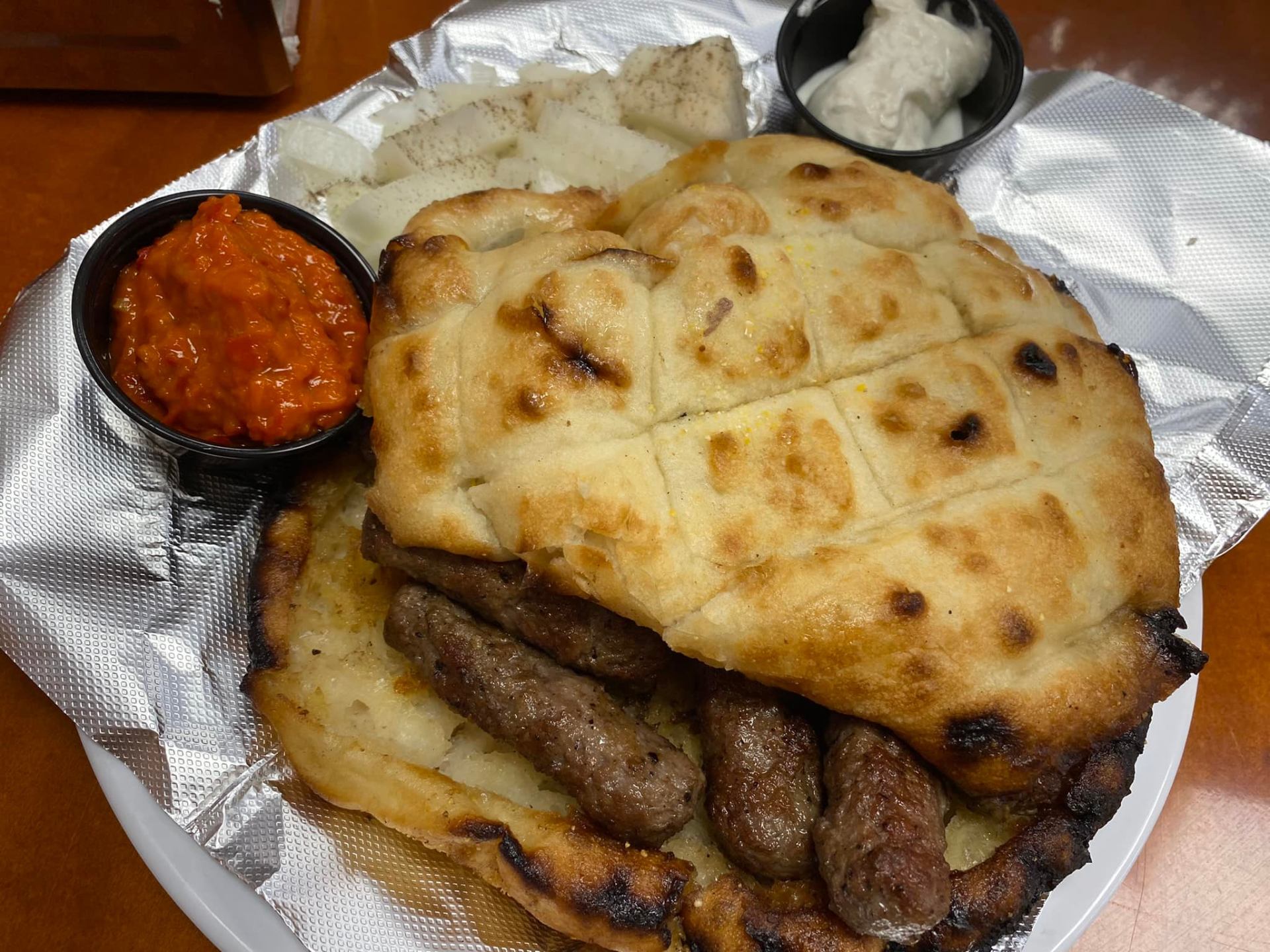 Bosnian ćevapi platter with fresh somun bread, ajvar and kajmak from the hot food counter