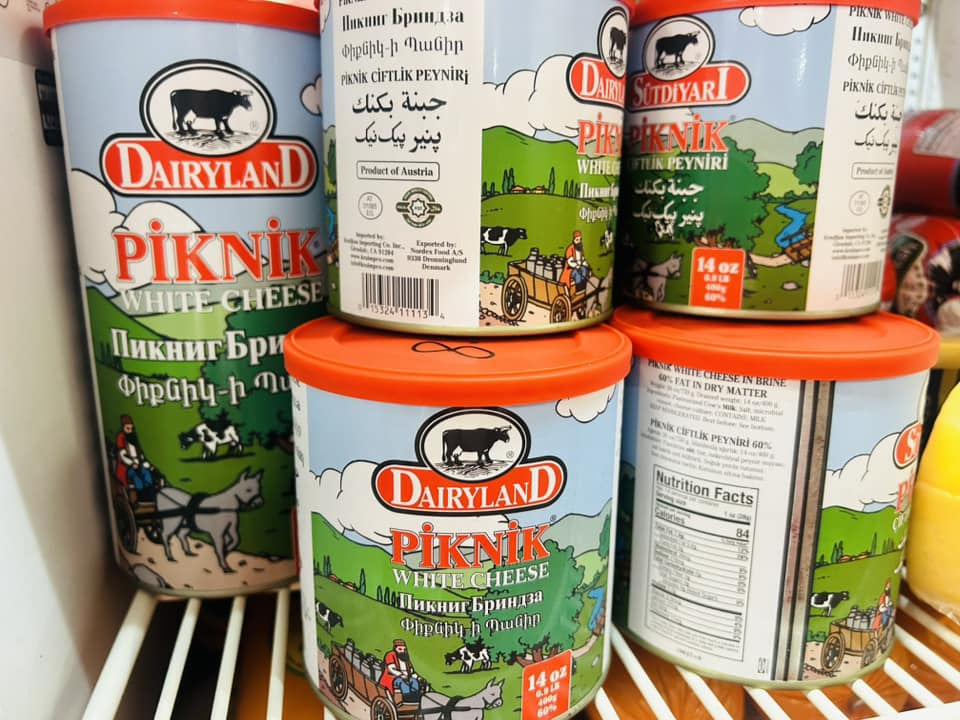 Tins of Dairyland and Sütdiyari Piknik white cheese stacked in the cooler