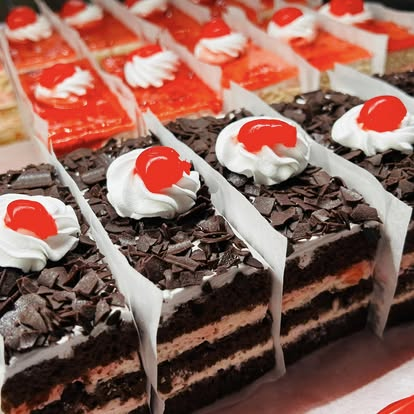 Chocolate layer cake squares topped with cream and cherries